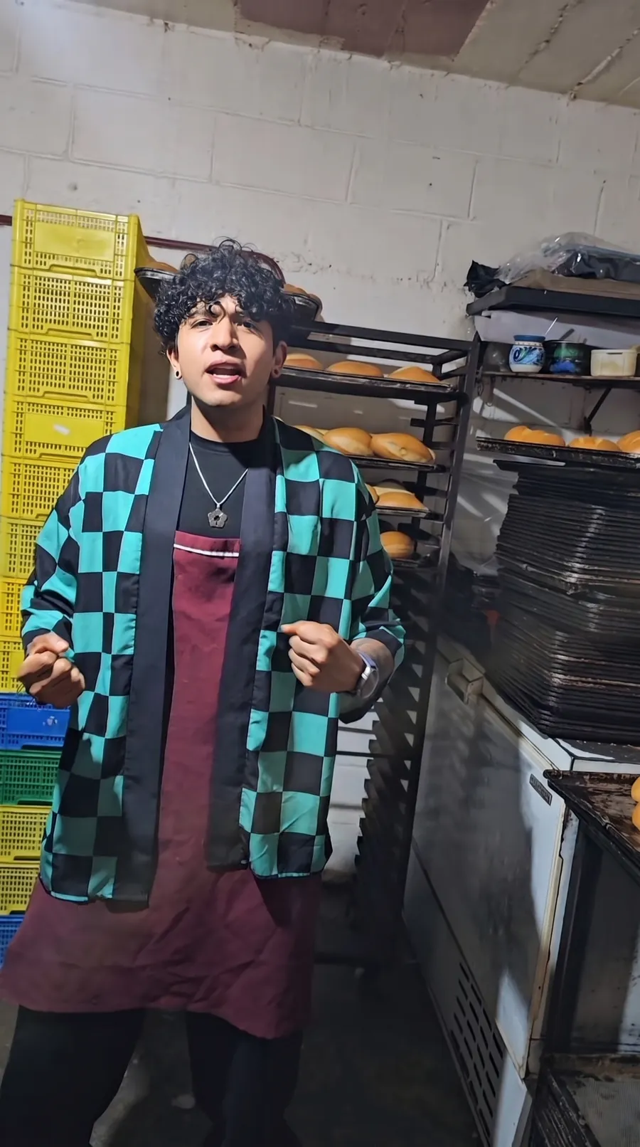 Juan con el haori entre racks de pan, en la panadería de su familia